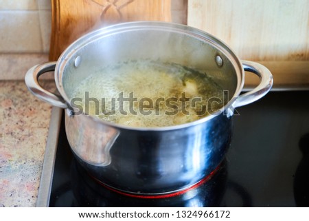Cooking broth in a saucepan on a glass-ceramic plate.