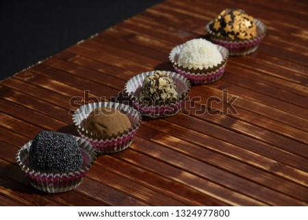 Chocolate Sweets Covered with Peanuts, Cocoa, Poppy Seeds, Candy Stars, Coconut Chips. Handmade Candies on Dark Background. Tasty Luxury Dessert
