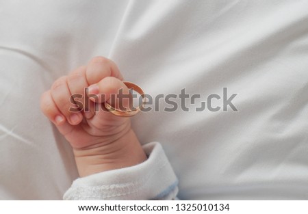 baby hand holding wedding ring Royalty-Free Stock Photo #1325010134
