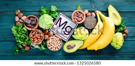 Foods containing natural magnesium. Mg: Chocolate, banana, cocoa, nuts, avocados, broccoli, almonds. Top view. On a blue wooden background. Royalty-Free Stock Photo #1325026580