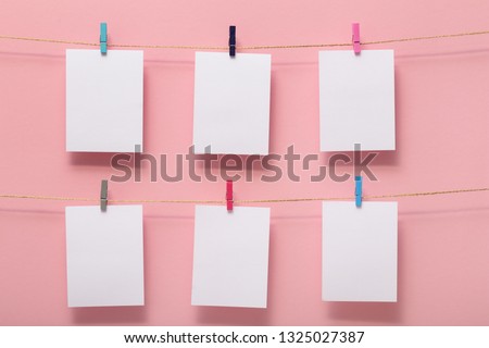 place for photo cards with happy moments of life, empty blanks attached to a linen rope in two rows with office clips on a colored background, template for text, images, idea for home decor
