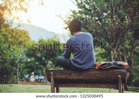 The young man travels nature on the mountain, is sitting and relaxing, reading a book in the flower garden.