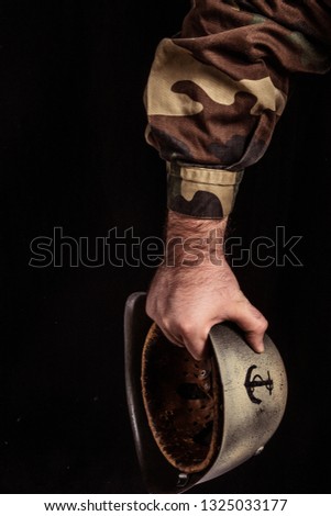 photography set of a soldier holding his helmet after a battle