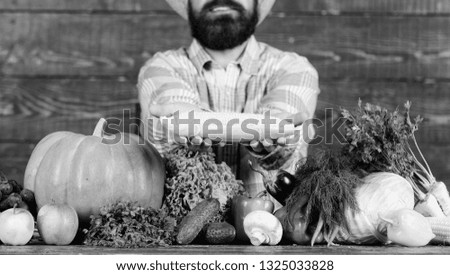 Farmer rustic villager appearance. Grow organic crops. Farmer straw hat presenting fresh vegetables. Man cheerful bearded farmer hold corncob or maize wooden background. Farmer with homegrown harvest.