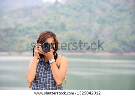 Hand woman holding the camera Taking pictures background Wang Bon dam Nakhon nayok , Thailand.