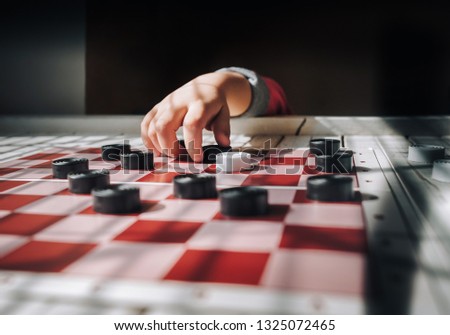 Children's hands on a checkerboard. The caucasian child plays checkers. Play board games. Loss, defeat, deadlock concept.