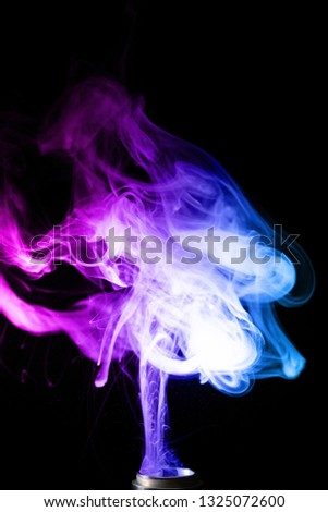 Vape clouds splash with two colours fog is blue and purple colour. Low light photo. Stock isolated on black background color smoke with spray boiling glycerine lines.