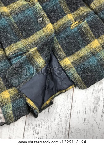 Details of green checkered coat on wooden background