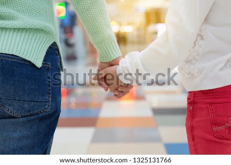 Mother and a child holding hands in shopping mall. Close up