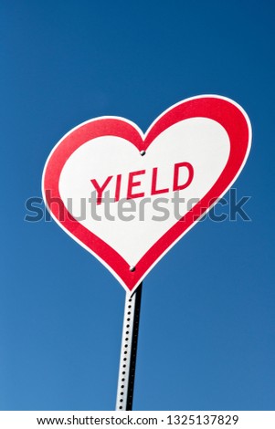 A heart shaped yield sign against a blue sky with copy space