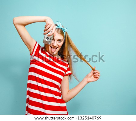 Blonde woman who is ready for summer travel with camera on a blue background