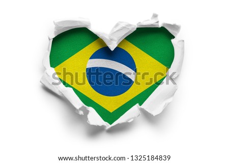 Heart shaped hole torn through paper, showing satin texture of flag of Brasil. Isolated on white background