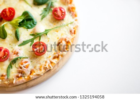 close up top view of pizza with tomatoes and herbs and copy space over white background