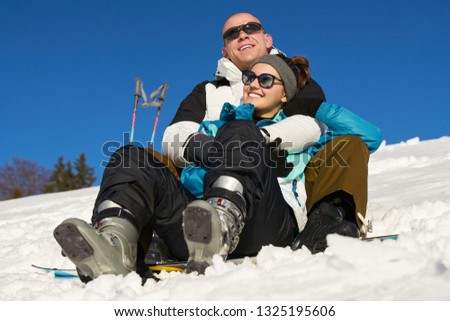 young couple resting on a snowy mountain after skiing