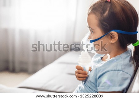Little girl in a mask, treatments respiratory tract with a nebulizer at home Royalty-Free Stock Photo #1325228009