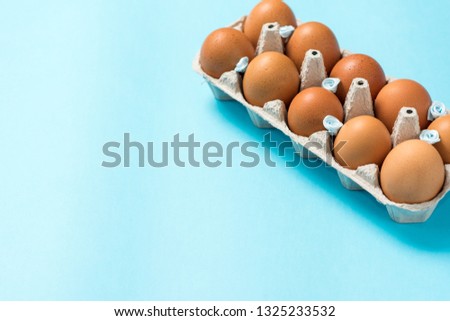 Brown Easter eggs in an eco carton pack lie on a beautiful blue background. Easter ideas. Space for text. Happy easter.