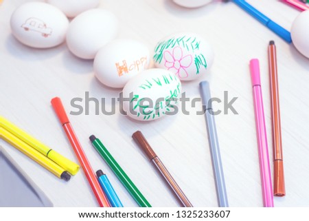 Easter eggs with children's drawings are on the table with markers. Easter ideas. Space for text. Happy easter.Toned image.