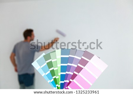 Color swatches for room painting. Young man in background (intentionally blurred) painting. (Shallow DOF)