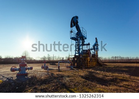oil production tower while working against the bright sun and blue sky