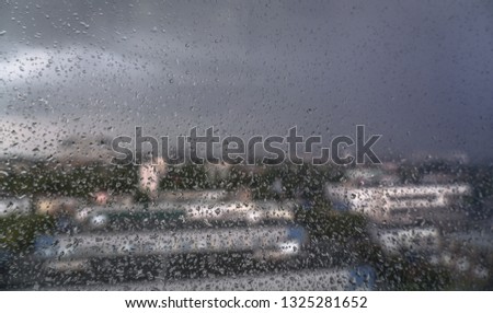 Window overlooking the spring-summer rainy city. Glass with fine drops on it. Stock background, photo