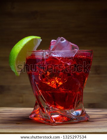 close up of a refreshing classic cocktail with vodka and cranberry juice served on the rocks with a lime wedge garnish with a wooden background