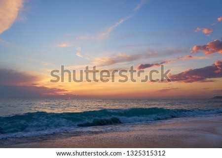                                Colorful sunset at the tropical sandy beach, waves with foam hitting sand. Copy space.