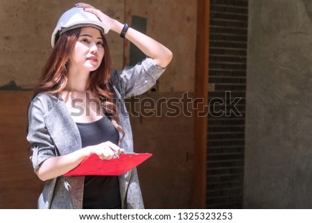 Engineer young woman wearing white helmet stand at outdoor holding some documents on site job. Architect women wearing construction hard hat or helmet checking work in progress at cons