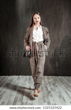 Professional studio. Attractive female person putting hand into pocket and looking straight at camera