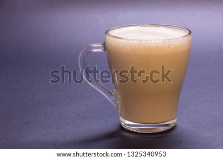 Transparent glass cup with coffee on blue background. Bright tone, soft focus Royalty-Free Stock Photo #1325340953