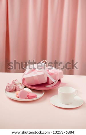 Happy woman/mother"s Day image of a coffee or tea cup and lisianthus flower with macaroon and gifts beside on drapes of pink. 