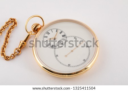 Round hand held , gold-tone watch with white dial and black numerals and gold hands on gold chain isolated on white background. 