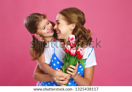 happy mother's day. child daughter congratulates mother and gives a bouquet of flowers color pink background

