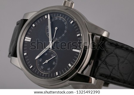 Men's watch with black leather strap,black dial, in silver body,stopwatch, silver clockwise and numerals isolated on gray background. 