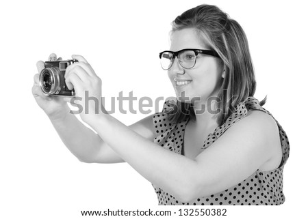 Retro black and white monochrome of beautiful young blond woman holding an antique camera. Hair teased up in bun. Photo in studio on white background and in Black and white.