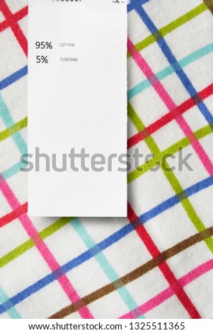 Fabric composition clothes label on colorful textile background closeup