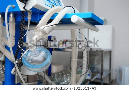 Oxygen mask as part of artificial lungs ventilation machine in surgery room, closeup. Space for text Royalty-Free Stock Photo #1325511743