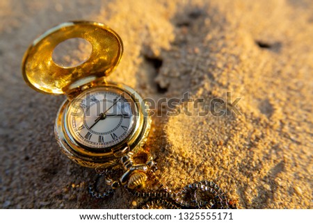 Vintage Pocket watch with morning light on sand floor. Selective focus and closeup.