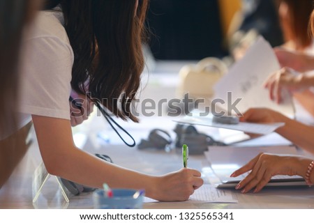The student in the uniform had using the pen to register into the paper.