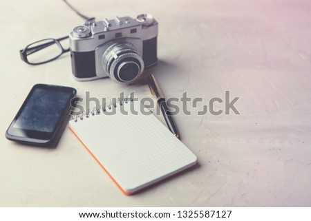 Retro photo film camera with note books, pen on light background