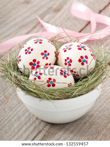 Easter eggs in a bowl decorated with a nest on the wooden table