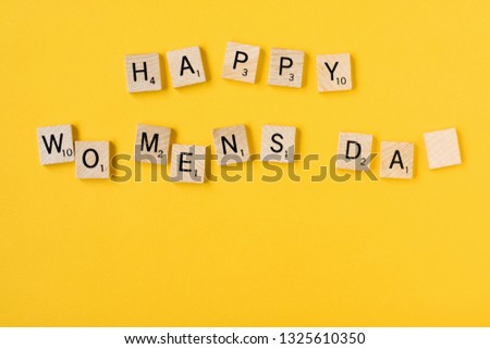 Top view Message happy woomans day spelled in wooden blocks on yellow background. Love, 8 march background. Gift, greeting, compliment concept. Copy space. place for text.