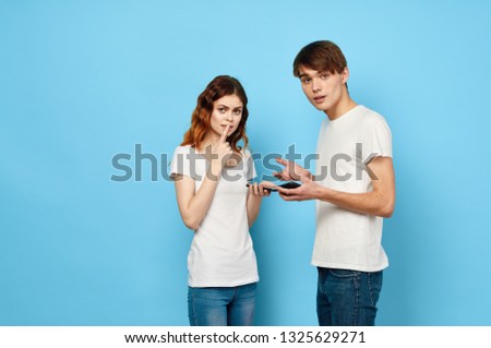 A woman and a handsome man on a blue background are holding the phone in their hands and asking for silence                          