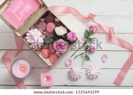 rose, desset and burning candles on white wooden background