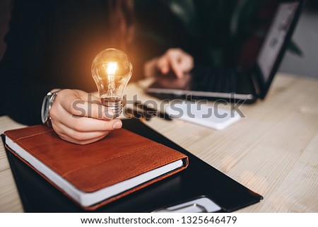 Business Woman holding light bulbs on the desk in an office and works on computer. Concept teamwork ideas with innovation and creativity