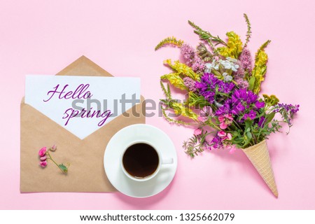 Bouquet of colored flowers in waffle cone, cup of coffee and envelope with card text Hello spring on pink background Greeting card Flat Lay Top view Concept.