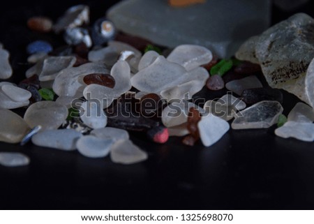 Polished glass chips on black background with gels closeup abstract texture background. 