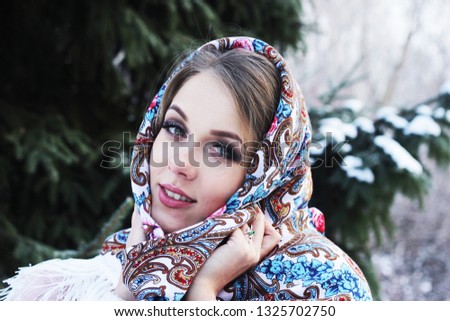 A lovely girl in a Russian traditional shawl in the winter forest Royalty-Free Stock Photo #1325702750