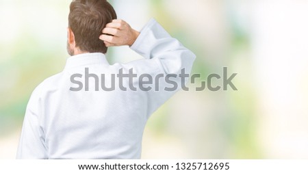 Handsome middle age senior man wearing kimono uniform over isolated background Backwards thinking about doubt with hand on head