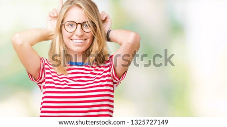 Beautiful young woman wearing glasses over isolated background Posing funny and crazy with fingers on head as bunny ears, smiling cheerful