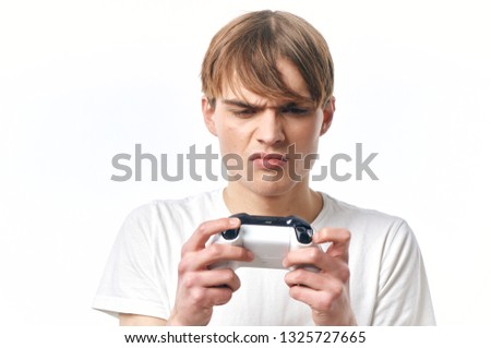 A young guy with a joystick in his hands on a light background                     